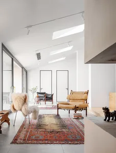 A minimalist living room with a red carpet and cushions on the floor.