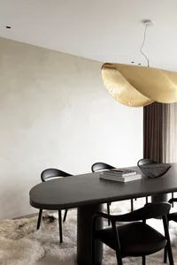 Modern dining room featuring a sleek metal table and chairs with a textured wall and plush rug.