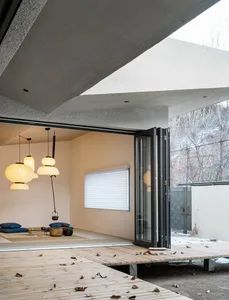 Modern living room featuring a wooden platform with hanging lantern lights and a sliding glass door leading to the outdoors.