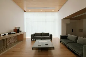 A minimalist living room with modern furniture and a wood laminate floor.