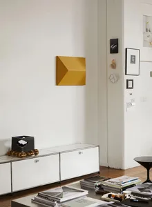 Modern minimalist living room featuring a white metal cabinet with a black top, gold balls, and various books and magazines.