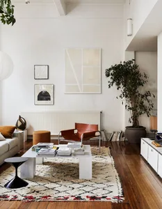 A modern minimalist living room with mixed materials including wood, leather, concrete, and textiles.