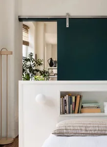 Minimalist bedroom with white walls, wood furniture, and metal accents.