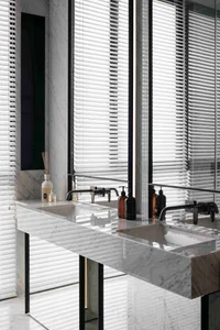 A modern, minimalist bathroom with white marble finishes and a sleek, floating sink.