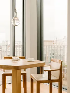 Modern dining room with wooden table, glass windows, and minimalist design.