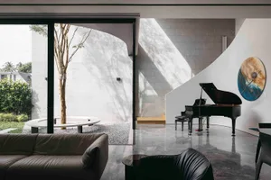A modern living room with concrete walls, a black grand piano, and large windows.