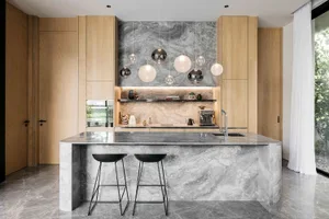 Modern, minimalist kitchen with marble countertops and hanging spherical lights.