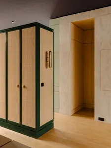 A green cabinet with woven doors in a wooden interior setting