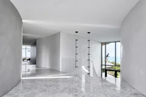 A minimalist residential interior with marble flooring, glass walls, and concrete accents.