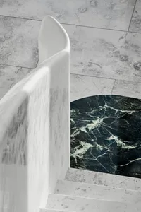 Modern marble staircase with curved handrail and textured floor.