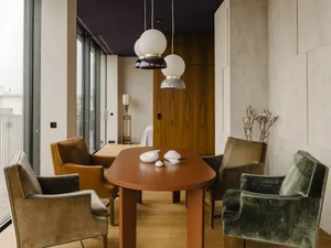 Modern minimalist dining room featuring a wooden table and velvet chairs with glass pendant lights.