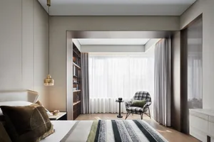 A minimalist bedroom featuring a striped rug, modern furniture, and a bookshelf against the wall.