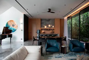 Modern living and dining area with marble flooring, indoor plants, and a mix of materials.