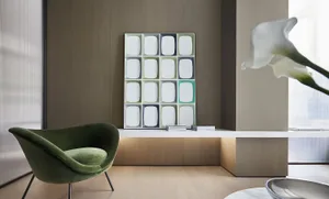 A modern living room with a green armchair, a colorful grid pattern artwork, and a sleek side table with a single flower arra