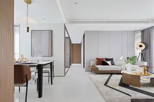 A modern living room with a long beige sofa, geometric rug, and a large abstract painting on the wall.