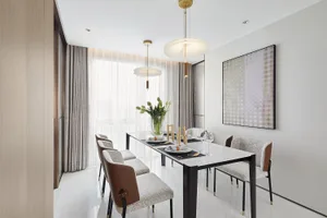 A modern minimalist dining room featuring a marble dining table, upholstered chairs, and pendant lighting.