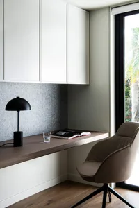 Minimalist office space featuring wooden desk, fabric chair, and metal lamp.