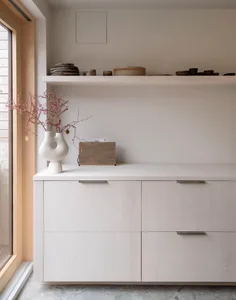 簡約室內空間，搭配木質家具與裝飾品，包括白色花瓶、樹枝與音響。