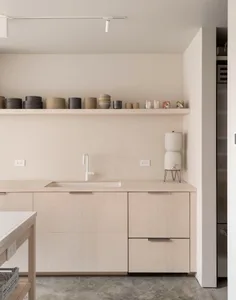 Minimalist kitchen interior with light wood cabinets and sleek, modern fixtures.