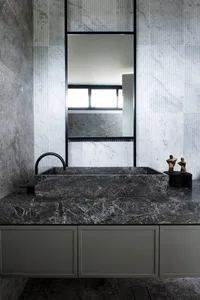 A modern marble bathroom with a sleek, dark marble countertop and sink, positioned under a rectangular mirror.