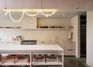 A modern minimalist kitchen with clean lines, light wood cabinets, and a white island.