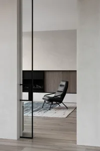 A modern living room features a black leather chair on a textured rug.