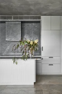 A minimalist kitchen featuring natural stone counter tops and a marble backsplash.