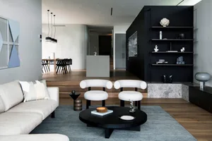 Modern living room featuring a concrete and black metal design with white furniture and a circular coffee table.