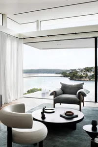 A modern living room featuring wooden cushions and a large window overlooking a scenic view of a river and hills.