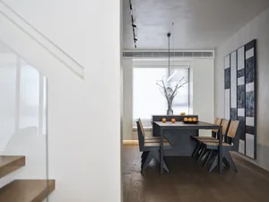 A modern industrial dining room with minimalist design, featuring a concrete dining table, wooden chairs, and a minimalist pe