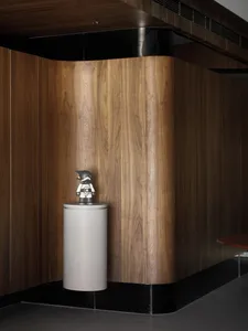 A minimalist lobby decorated with wooden paneling, featuring a small figurine on a pedestal.