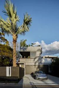 Modern residential house with a minimalist design, featuring concrete materials and greenery on the rooftop.