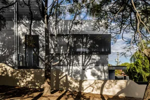 Concrete exterior of a modern building with trees casting shadows.