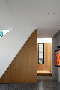 A modern interior space featuring wooden paneling, with a central wooden structure and a concrete floor.