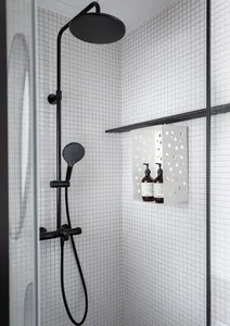 A minimalist bathroom featuring a shower with black fixtures and white square tiles on the walls.