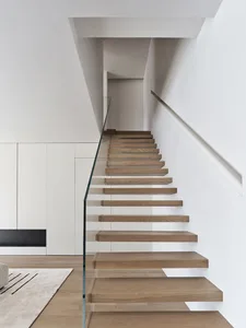 Modern staircase with white wooden steps and glass rail.