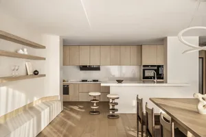 A minimalist residential kitchen featuring wooden finishes, white countertops, and modern appliances.