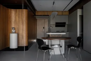 A modern kitchen with wood panel walls and a circular dining table.