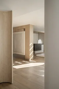 A modern minimalist living space with wooden flooring, marble accent wall, and concrete elements.