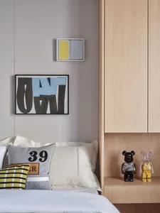 Bedroom with minimalist design featuring a bed with white sheets, colorful pillows, and a wooden headboard, with abstract art