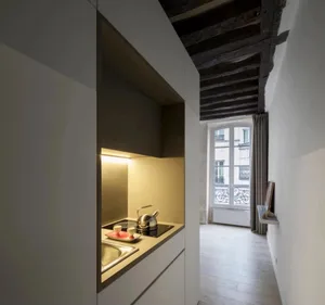 A sleek, modern kitchen with minimalist white cabinets, a sink, and a kettle on the stove.