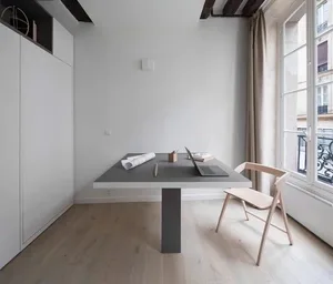 A minimalist office space featuring a modern concrete desk and wooden chair in front of a large window.
