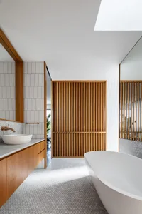 Modern bathroom with wooden accents, white tiles, and a freestanding bathtub.