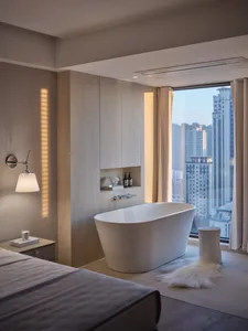 Modern minimalist bathroom with concrete walls and floor, freestanding oval tub, and city view from large window.