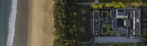 Aerial view of a residential building with a beachfront location and concrete, glass, and metal materials.