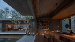 Contemporary residential interior featuring concrete walls, wooden furniture, and a serene outdoor pool area with greenery.