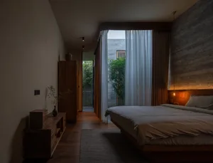 A minimalist bedroom featuring natural wooden furniture and soft, neutral textiles