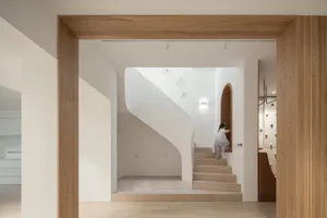 A minimalist interior design featuring wooden staircase and white walls with pendant lights.