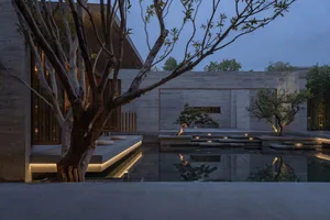 A minimalist residential space featuring concrete architecture and landscaping, illuminated at dusk.