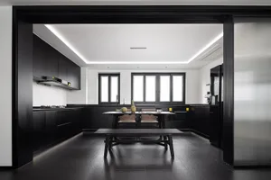 A modern, minimalist kitchen with black cabinetry and white countertops.